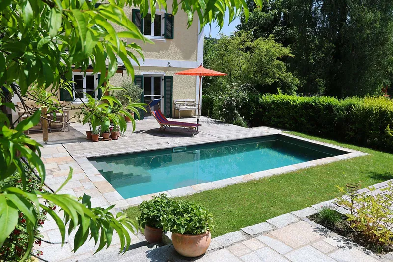 Privater Poolgarten mit Naturstein und ruhigem Wasser